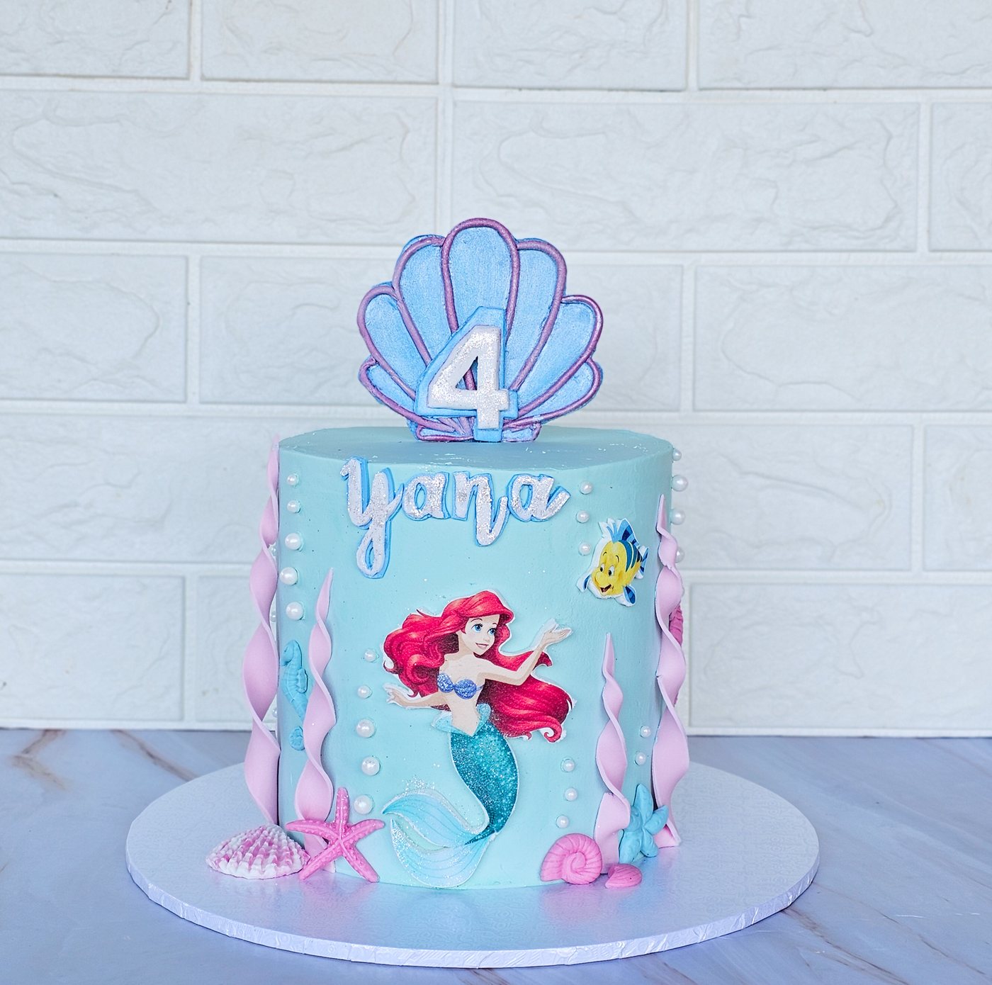 Aqua mermaid cake with a seashell topper, the number 4 and the name Yana