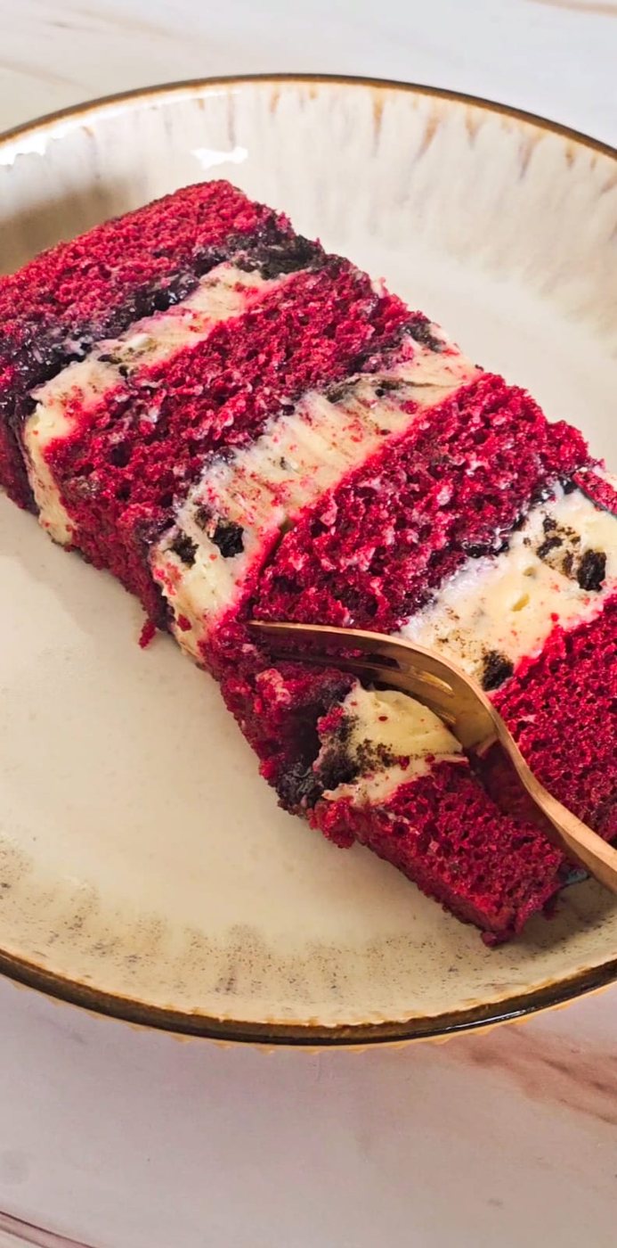 A slice of red velvet cake with cream cheese layers